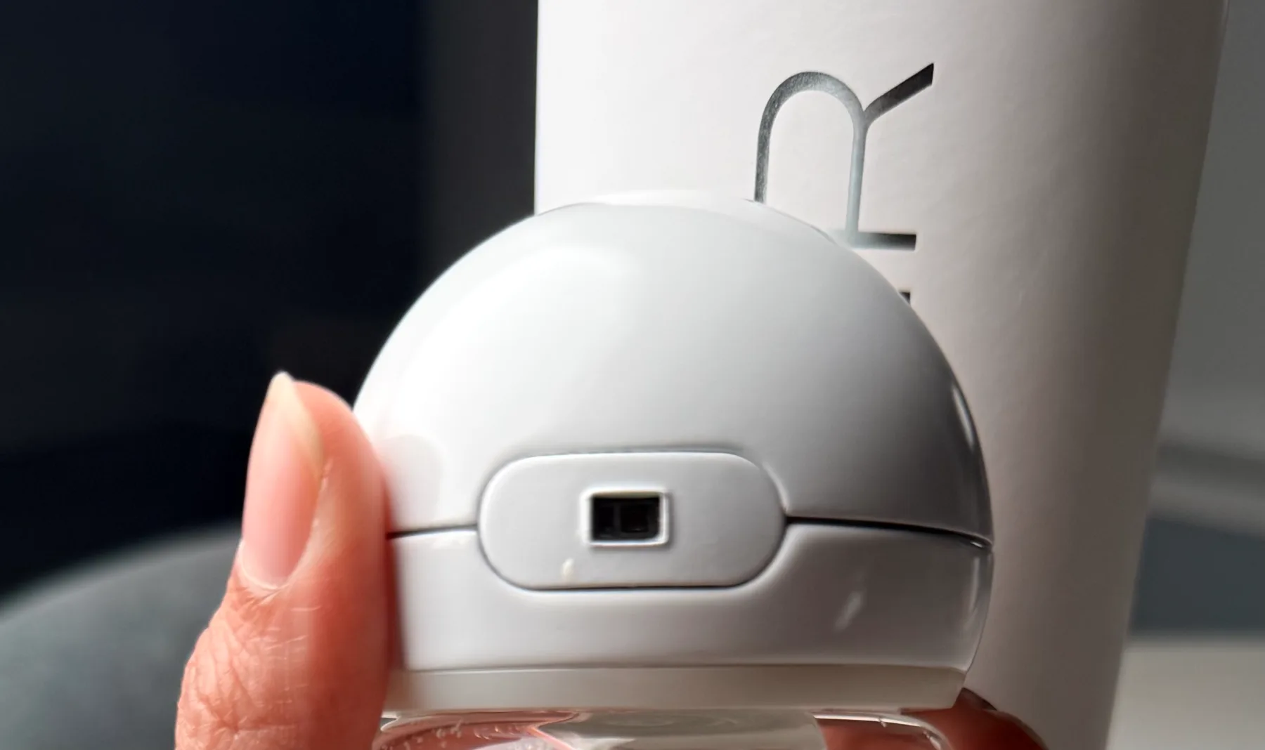 A fingertip beside the optical sensor window on the AQOIR cap